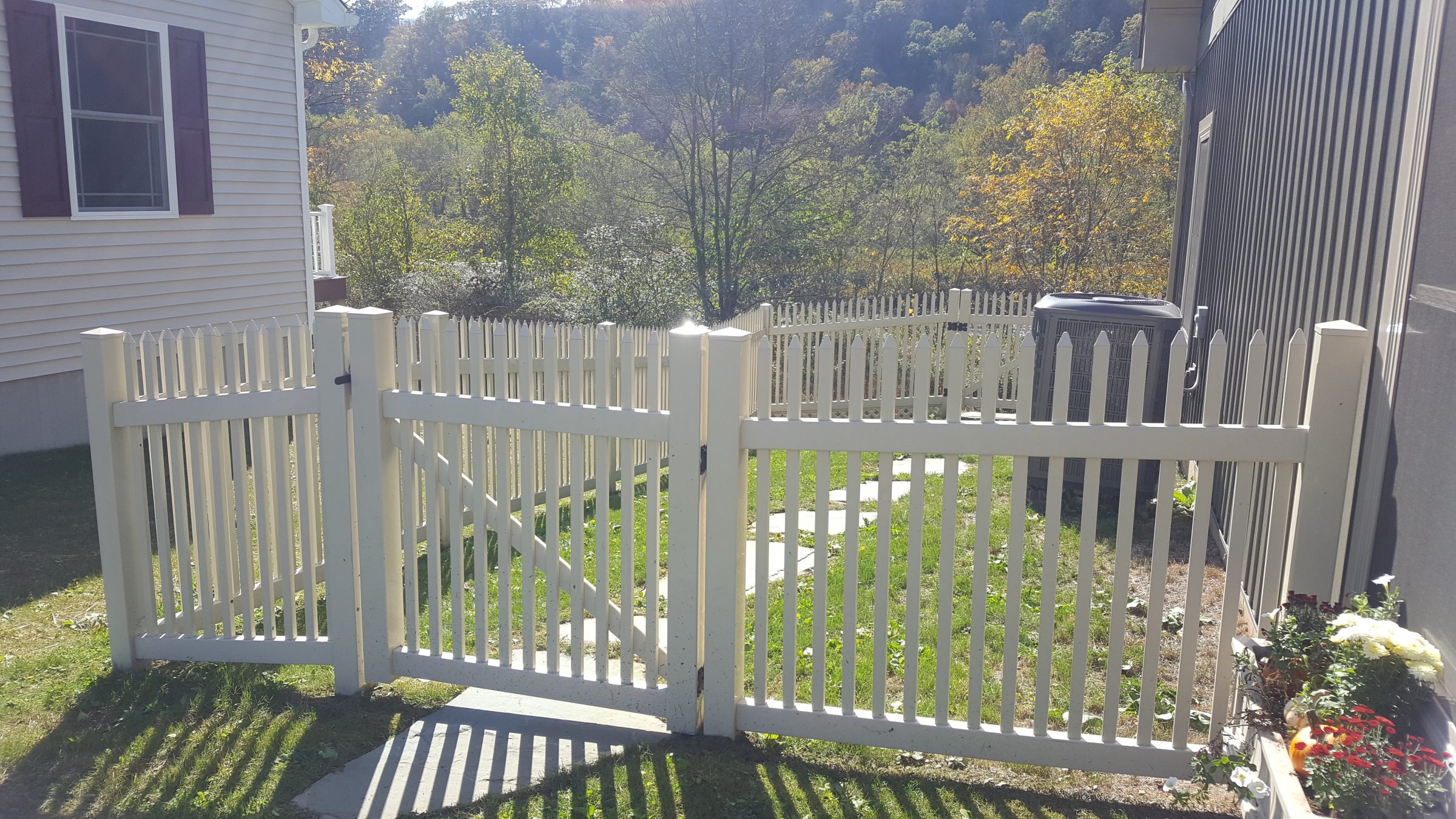 White picket fence with garden and trees