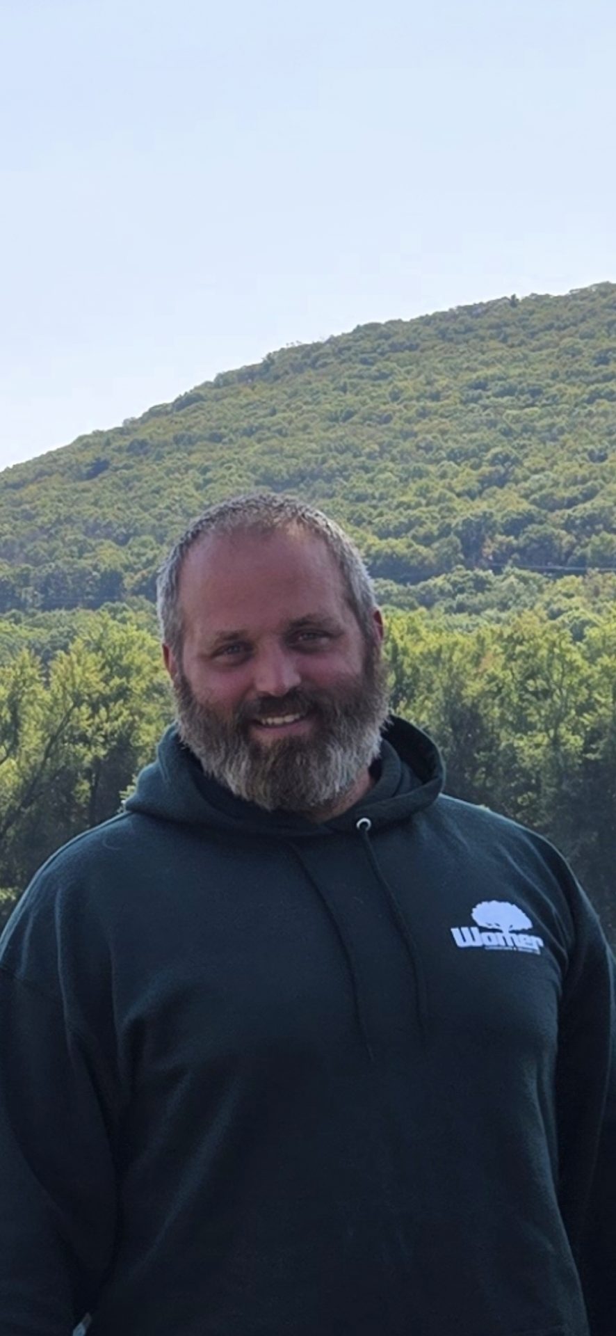 Man smiling in front of a green hill