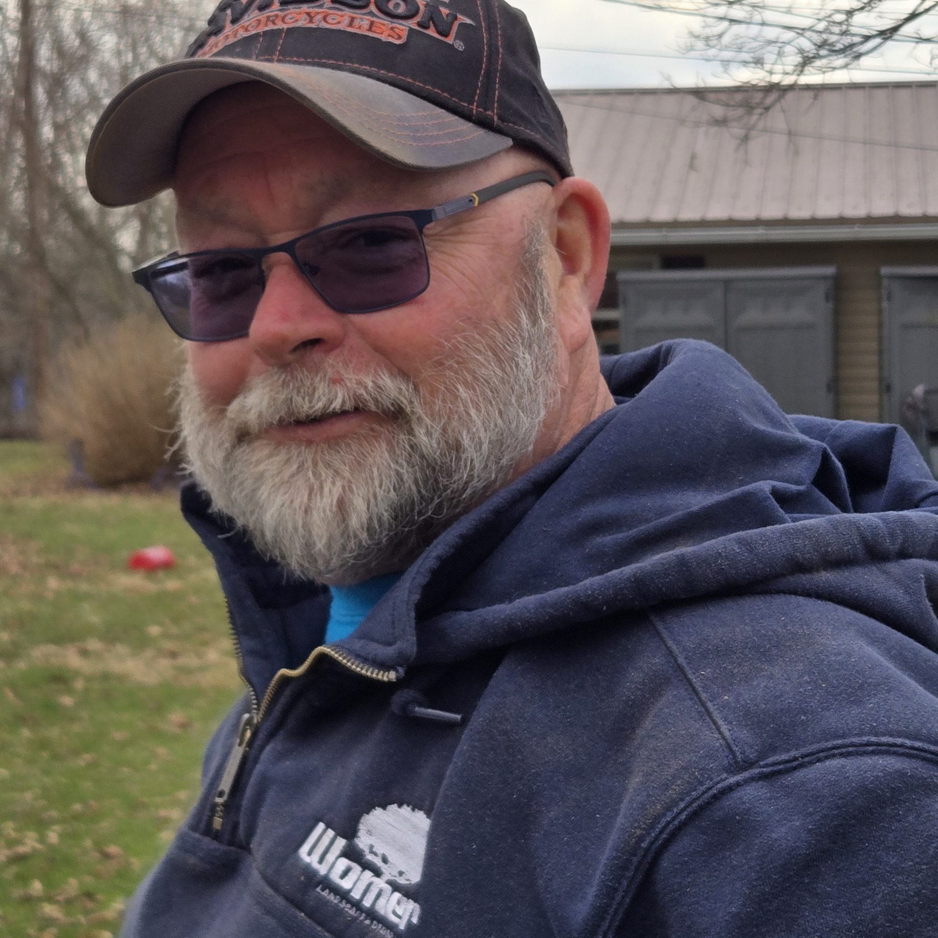 Man with a beard and hat outdoors.