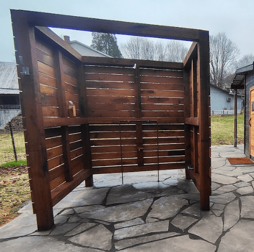 Outdoor wooden shower enclosure on stone patio