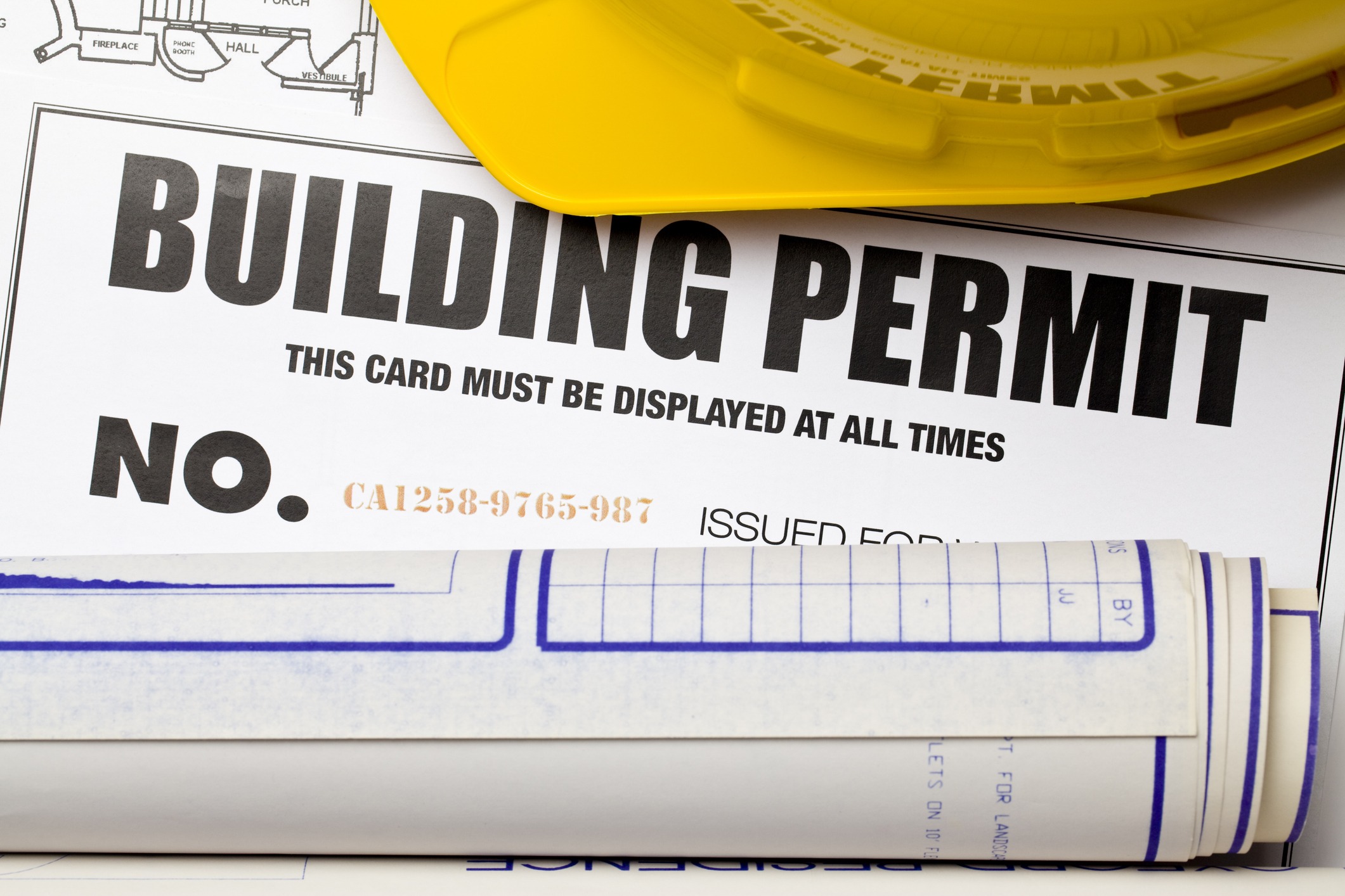 Building permit with blueprints and helmet.