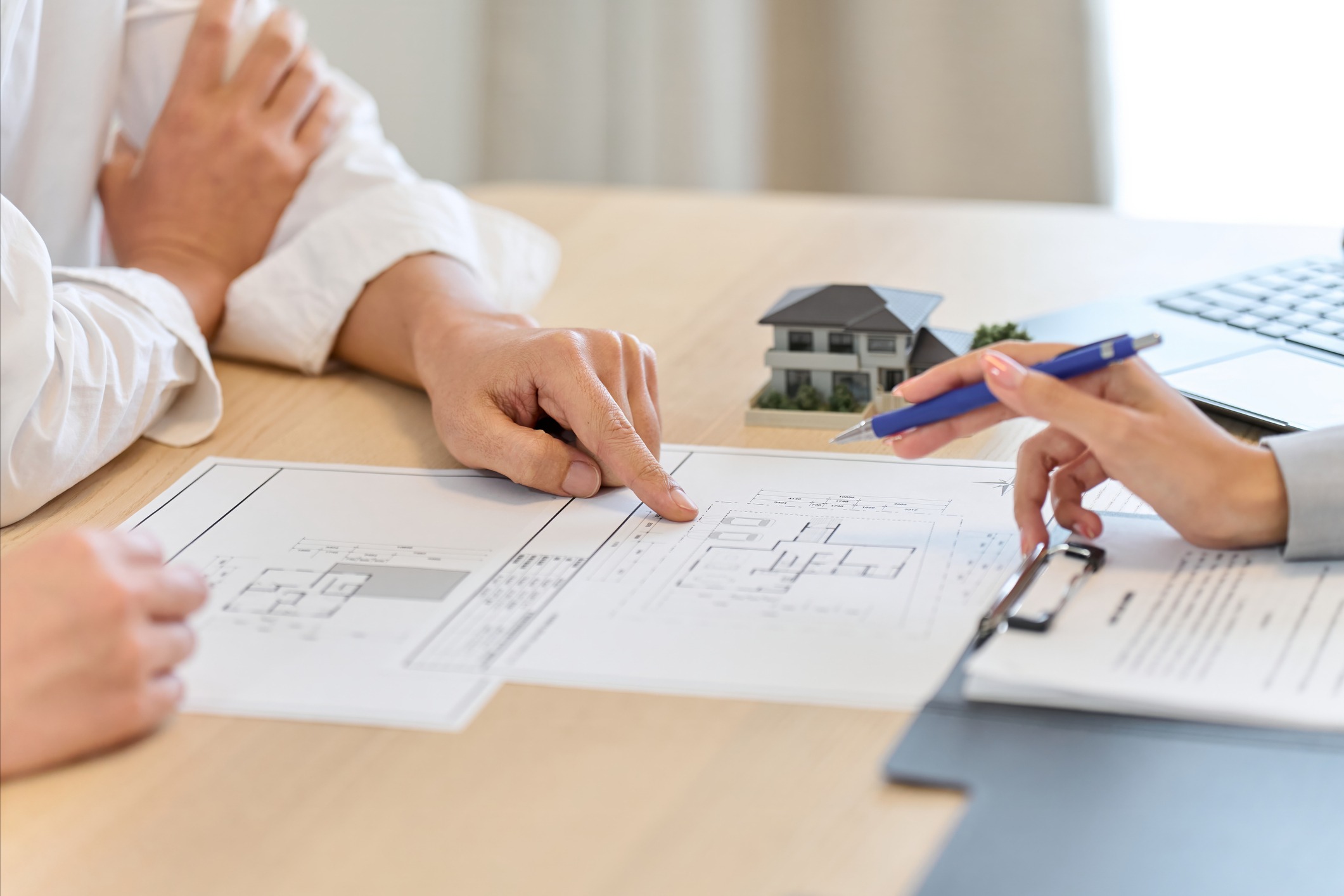 Hands reviewing architectural blueprints and model