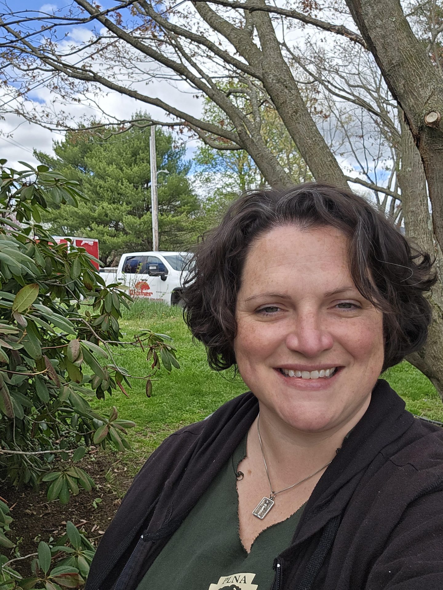Woman smiling outdoors with trees and truck behind