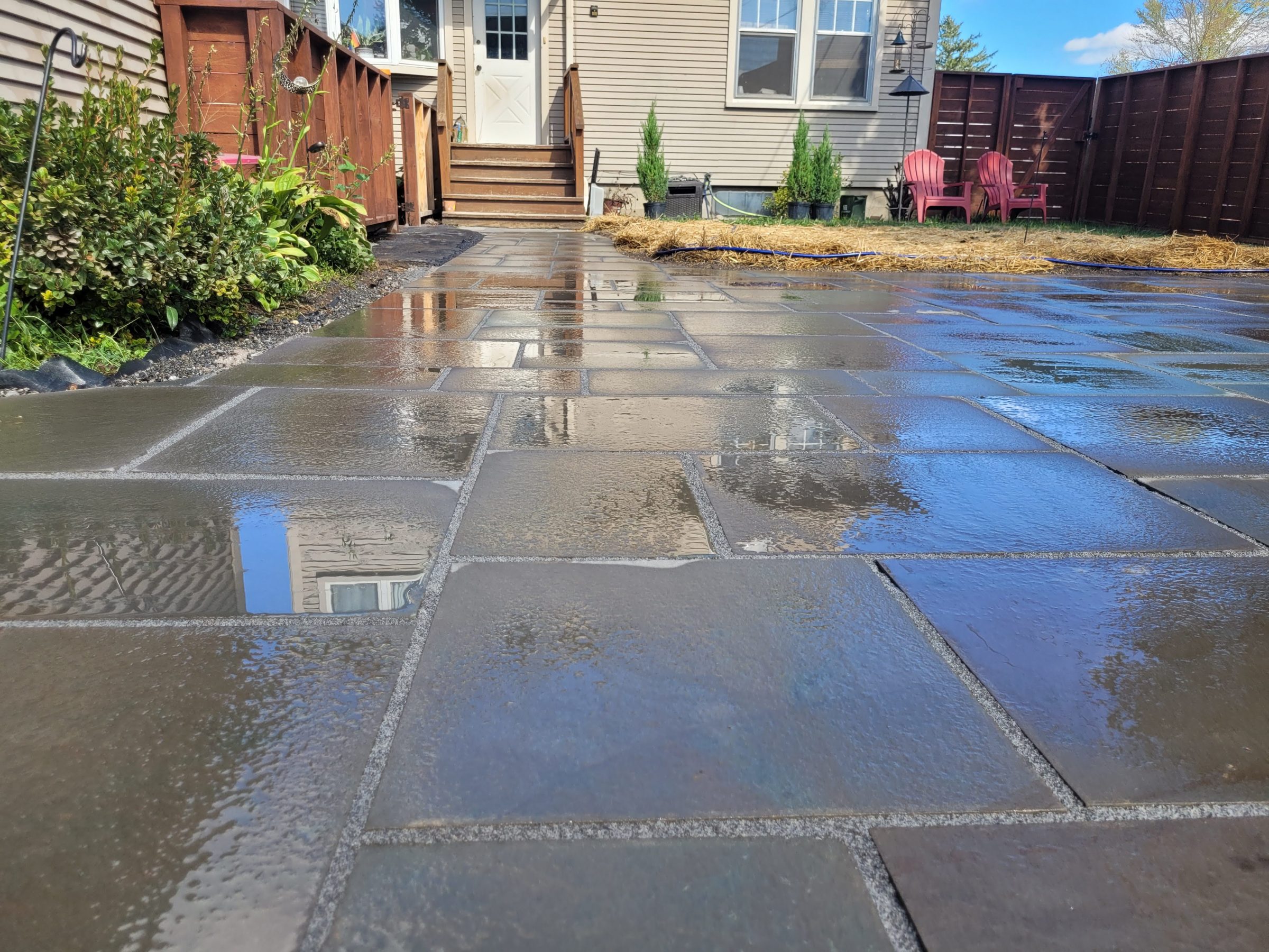 Wet stone patio with garden and chairs