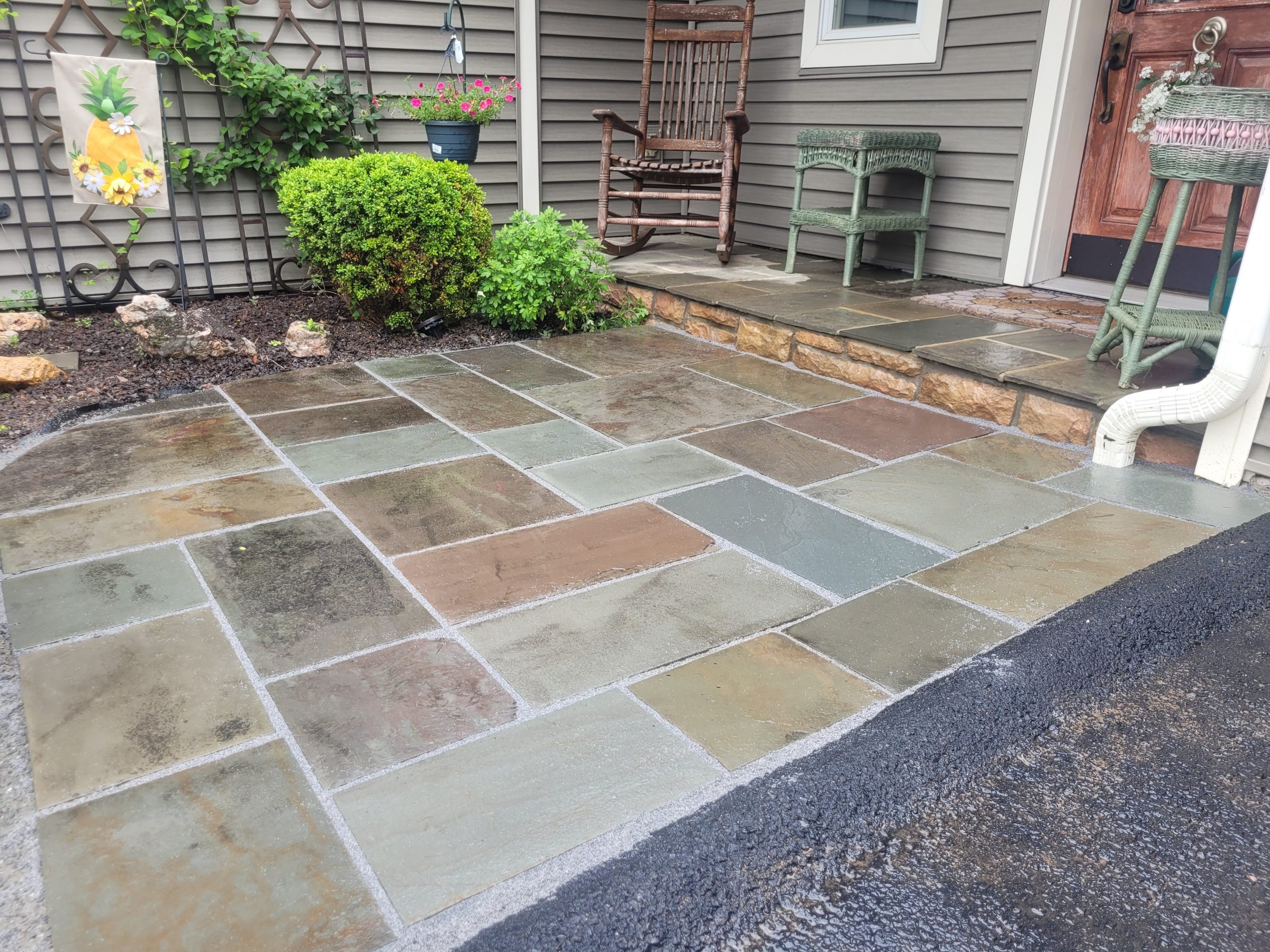 Rain-wet patio entrance with garden and chairs.