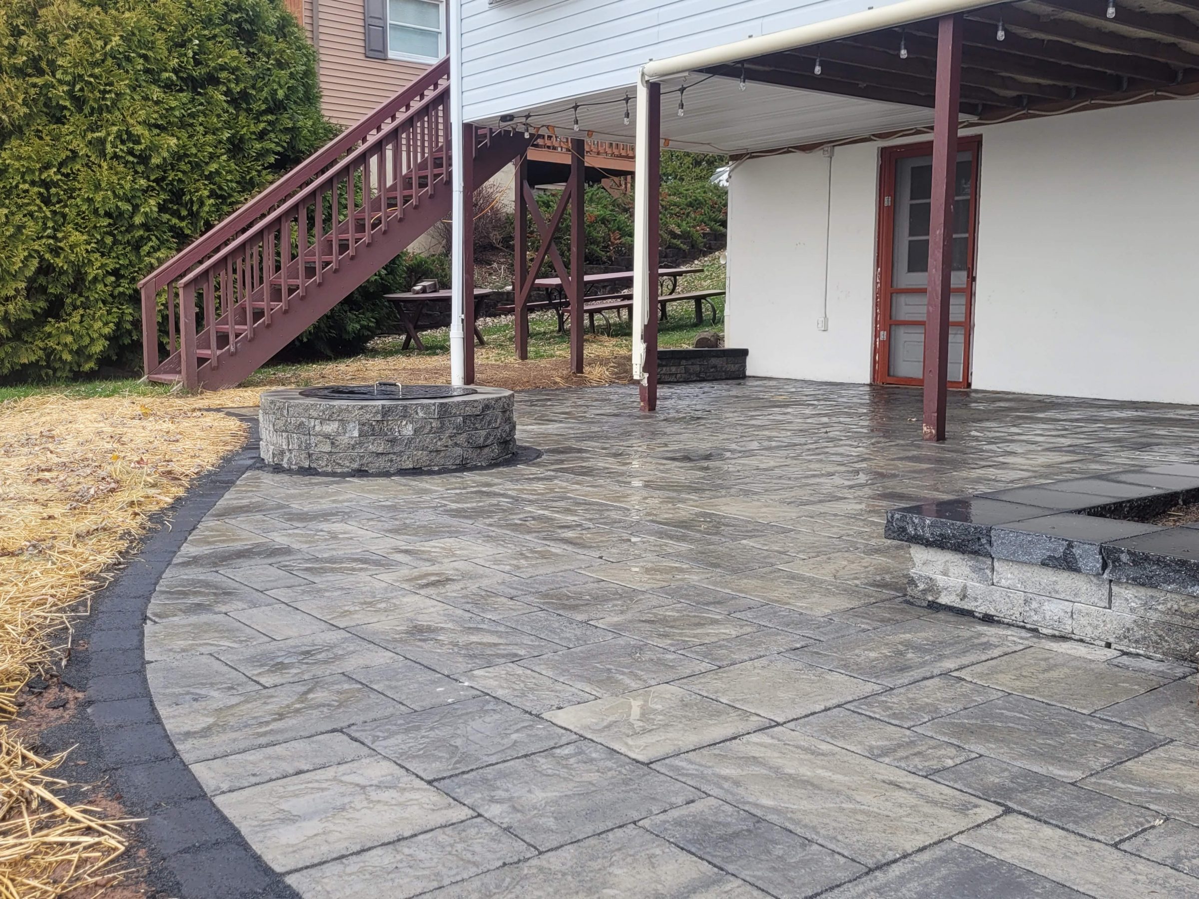 Outdoor patio with stone flooring and fire pit.
