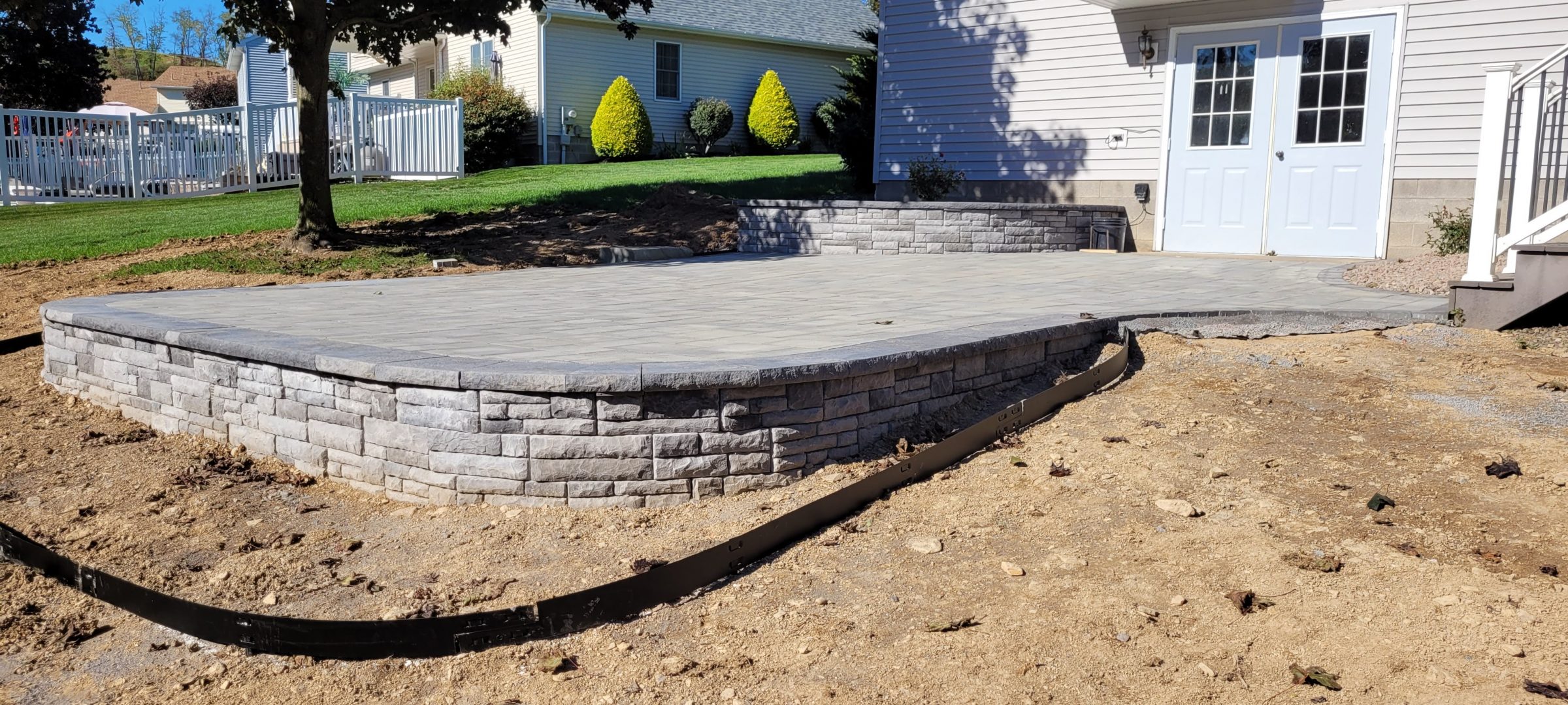 Raised stone patio with retaining wall in backyard
