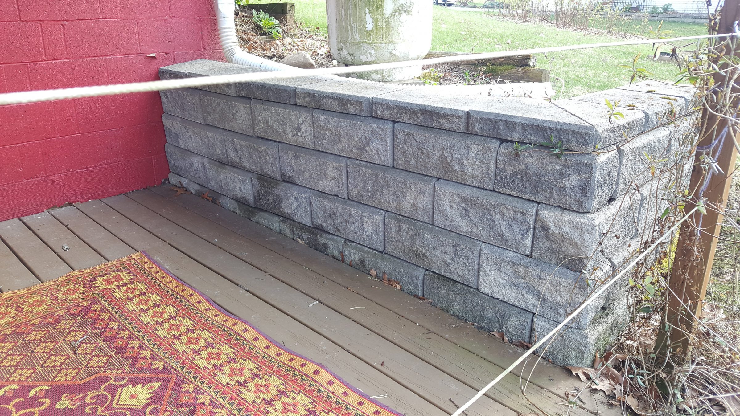Stone retaining wall beside red house exterior
