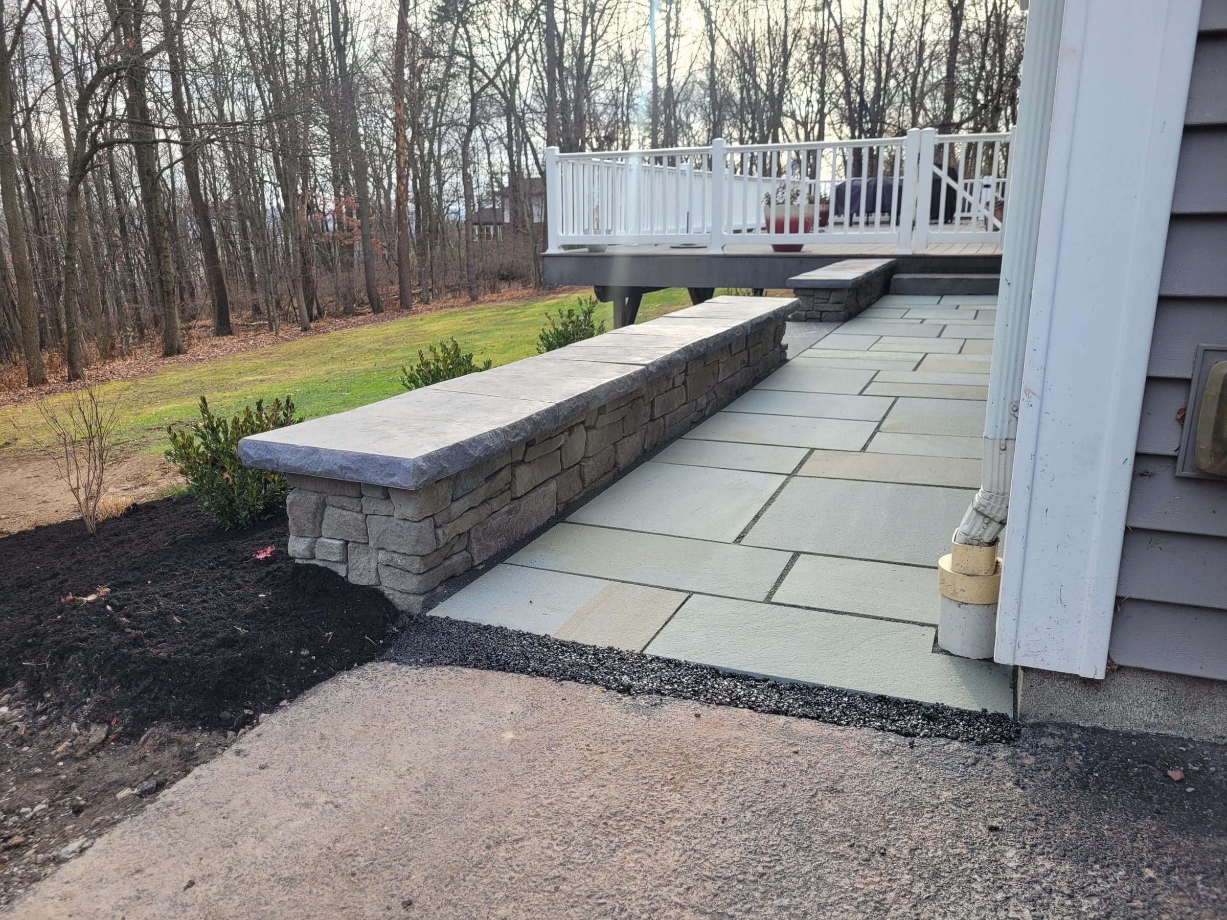 Stone patio with retaining wall and deck