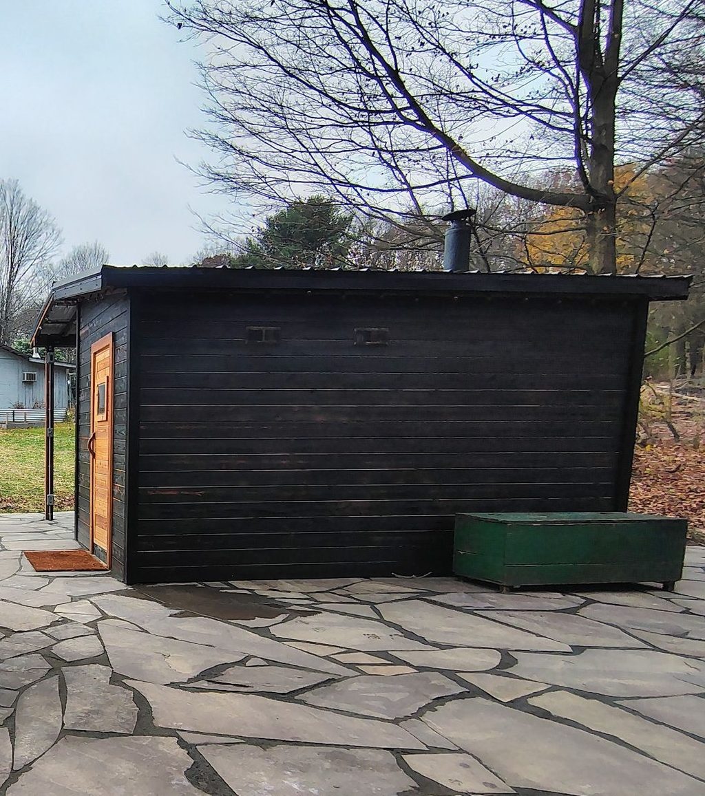 Outdoor wooden shower and black sauna cabin
