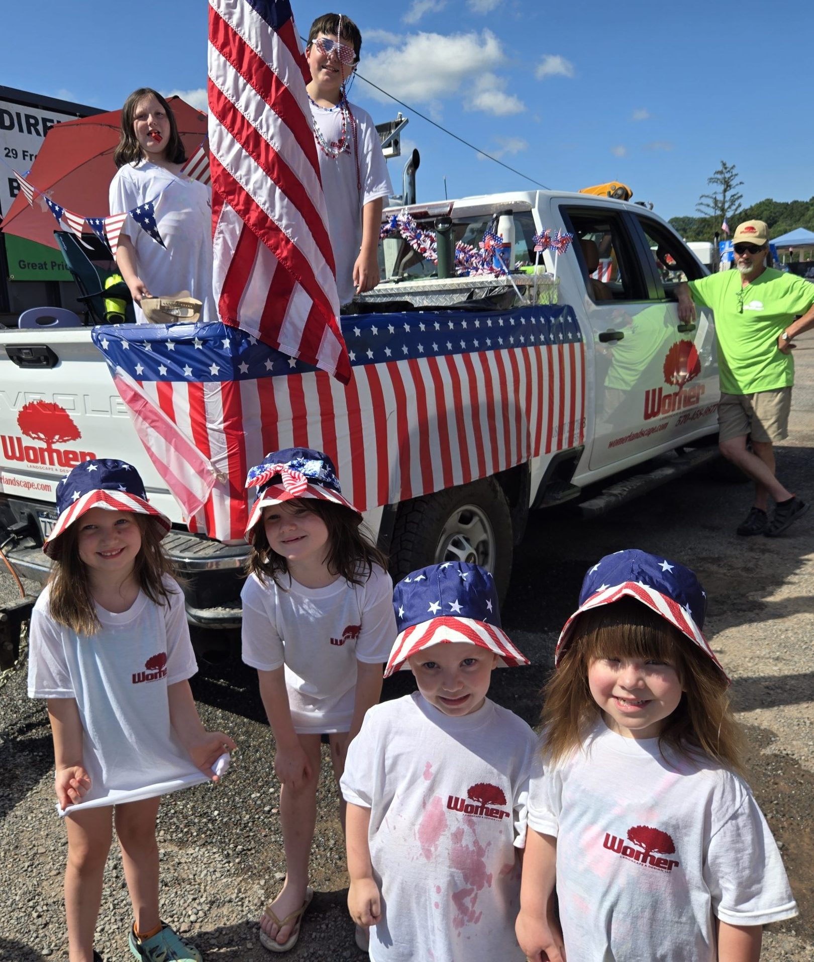 Children posing by patriotic parade truck with flags