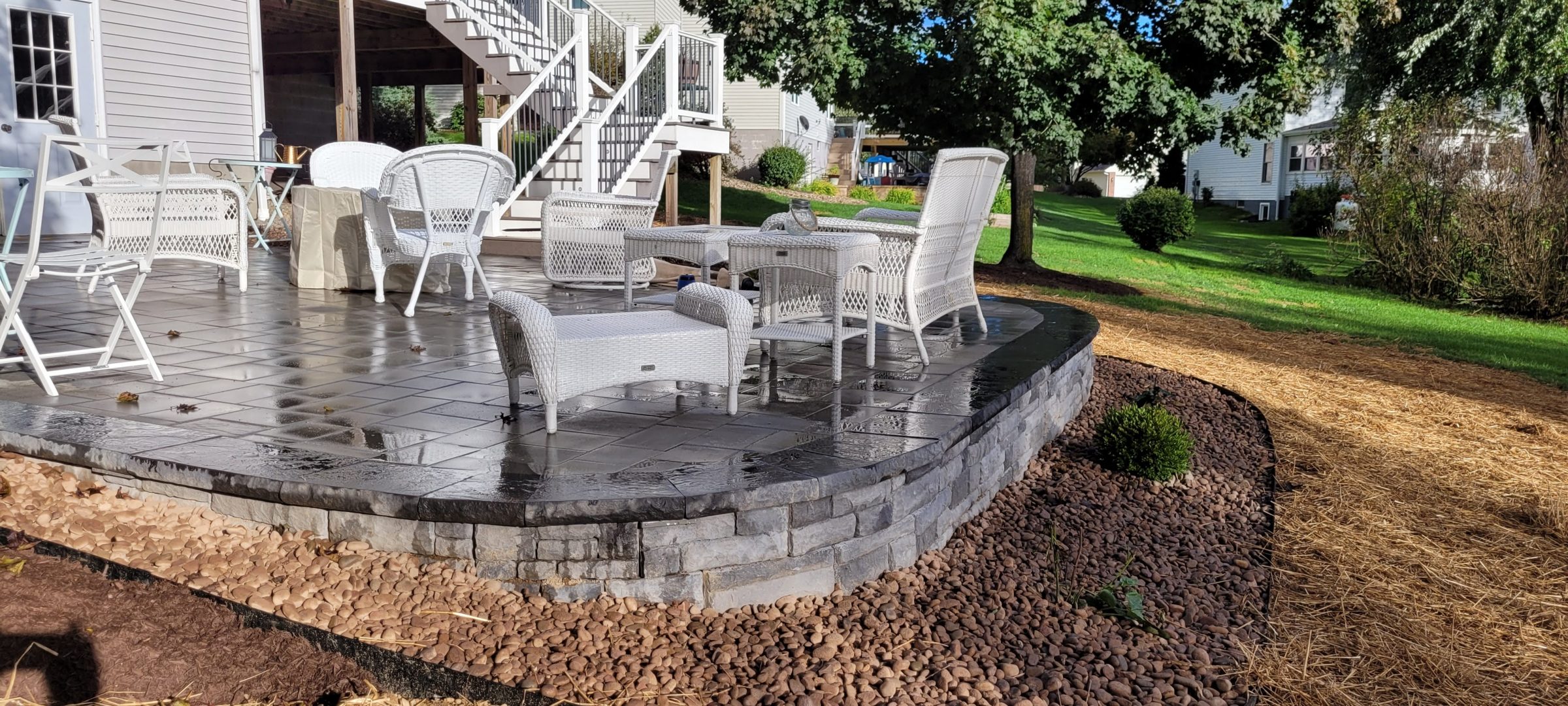 Backyard stone patio with white wicker furniture