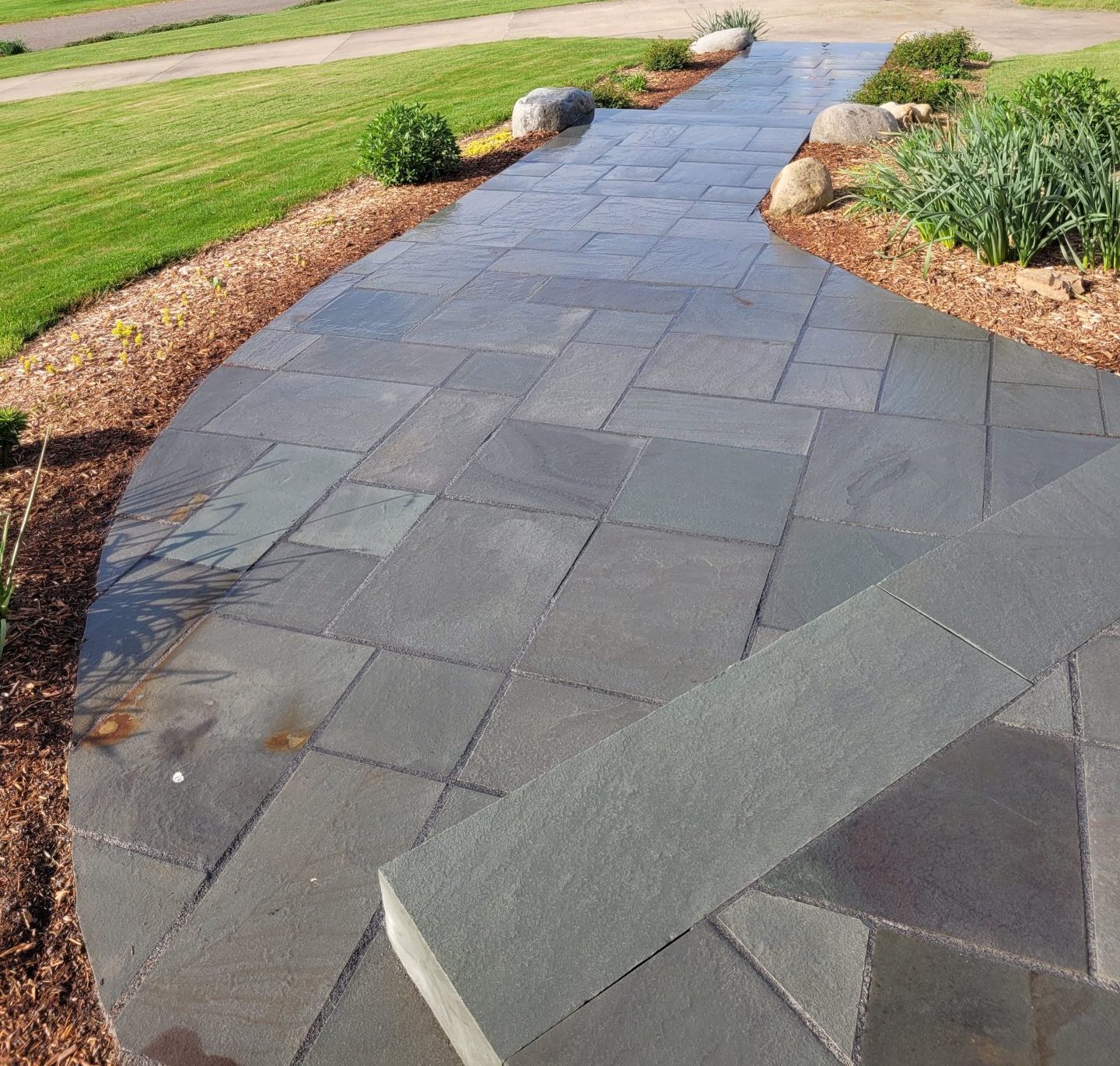 Stone walkway with landscaped lawn and driveway